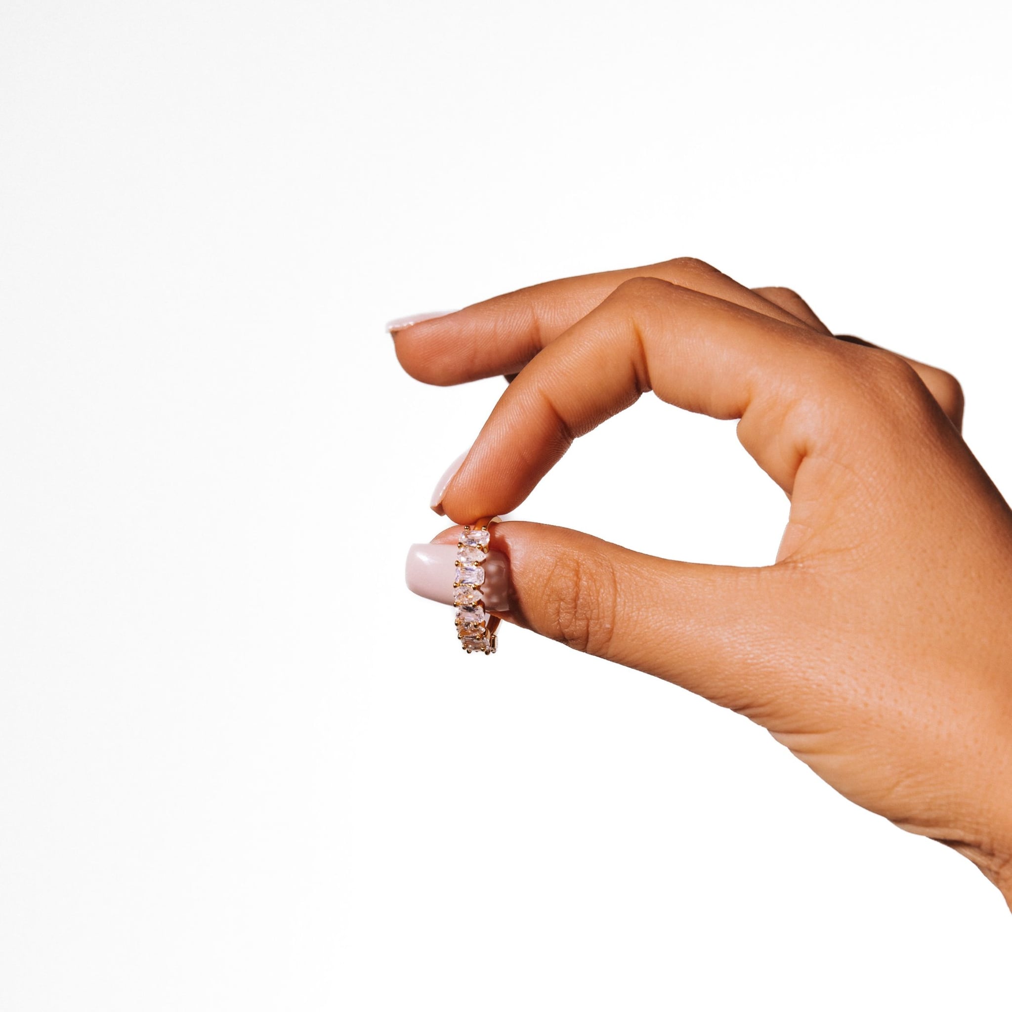 Ameena ring held between thumb and finger against a white background.