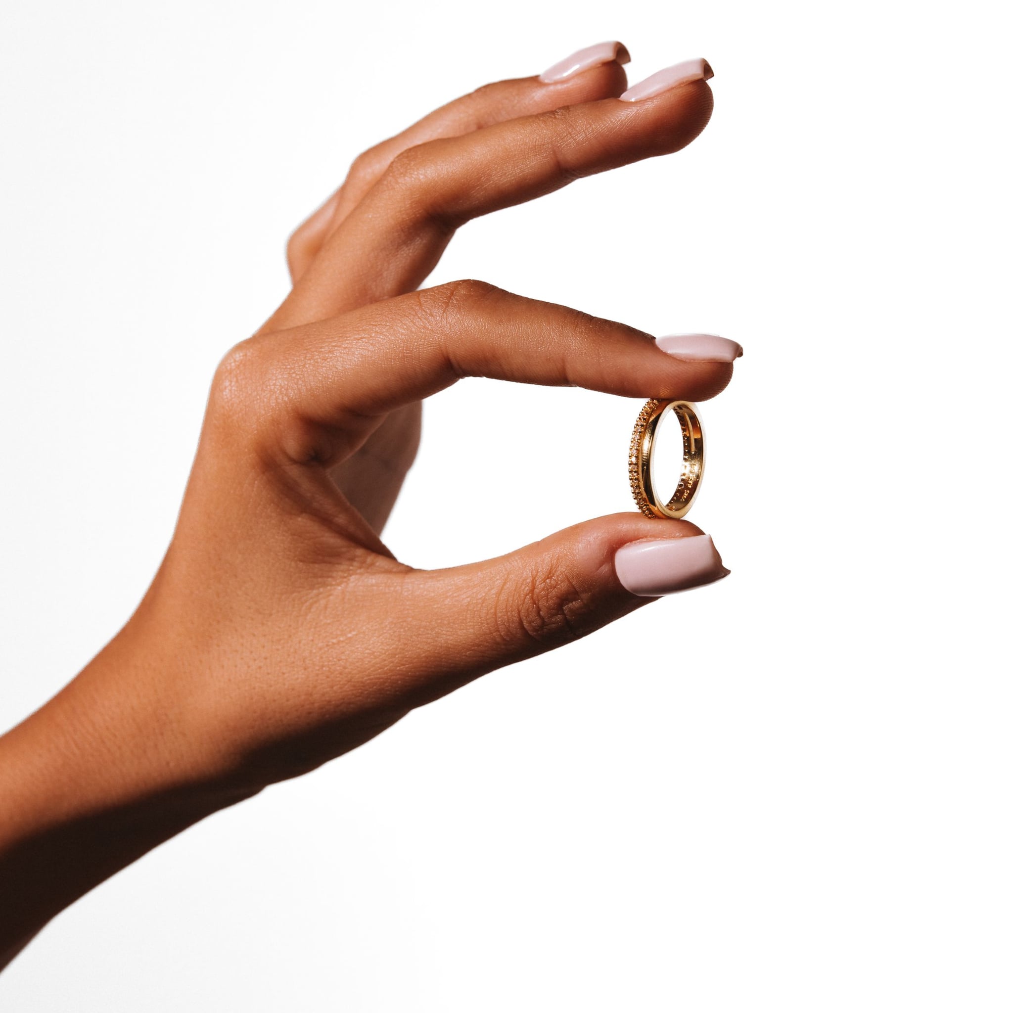 Inara ring held between thumb and finger against a white background.