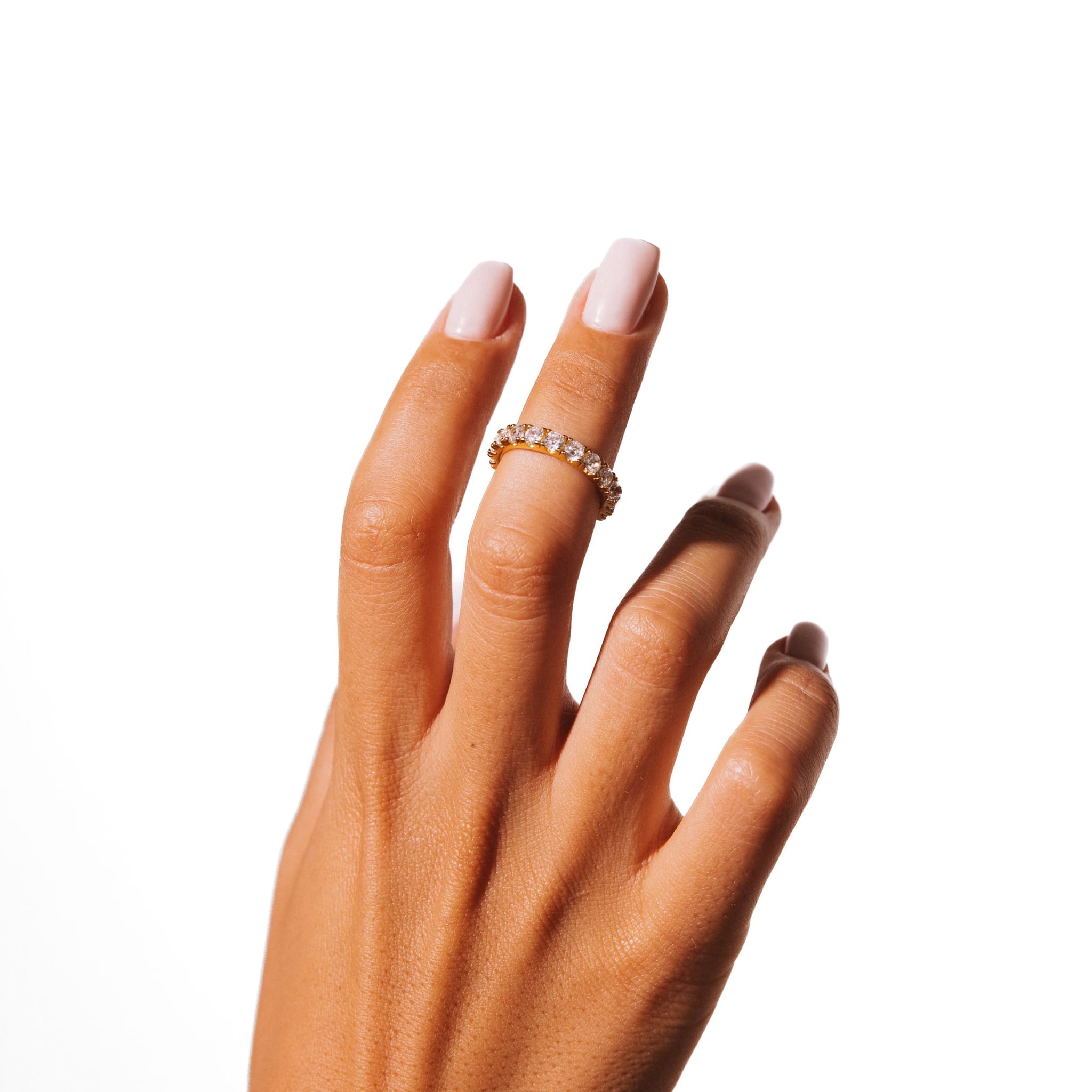 Lilly ring worn on a raised hand against a white background.