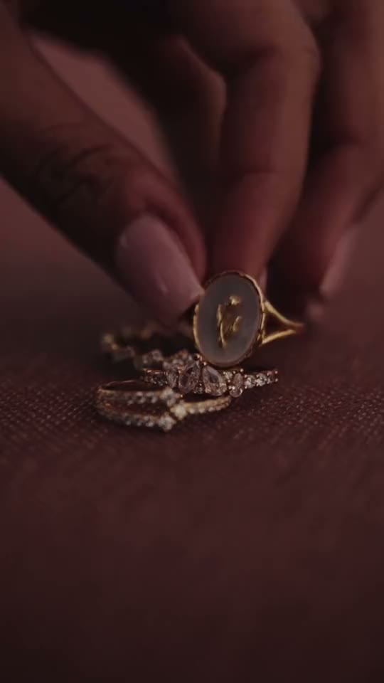 Short film: the Zahra ring set down on burgundy fabric, then a hand wearing the Jasmin hand chain, then hands at the waist of a burgundy outfit.